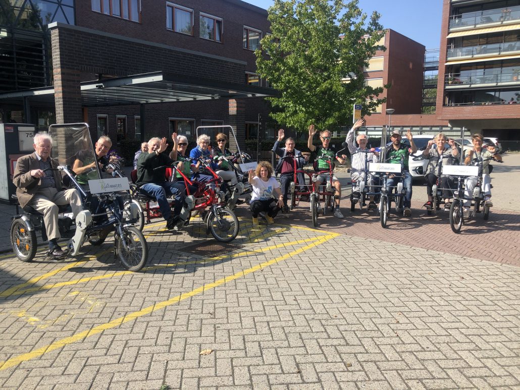 Groepsfoto van alle deelnemers en vrijwilligers op de fietsen.